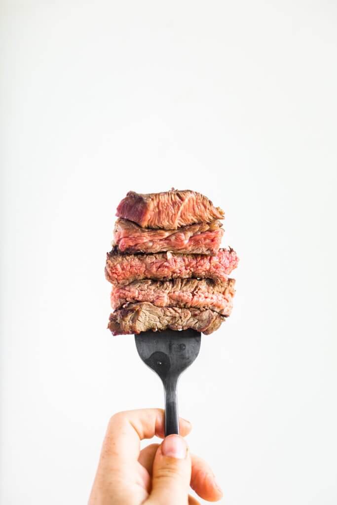 slices of beef on a fork with a white background to show beef doneness