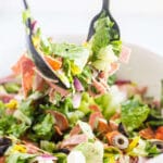 fork and spoon scooping out antipasto salad to serve it