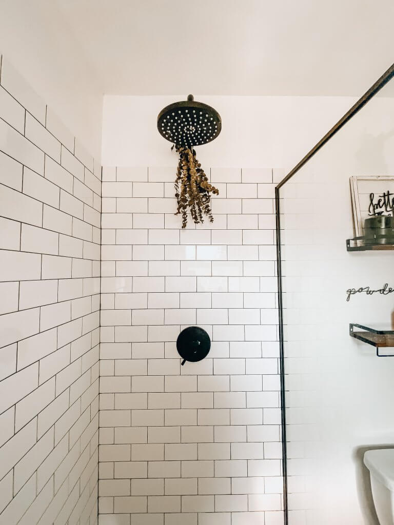 subway tile shower with rain shower head and eucalyptus