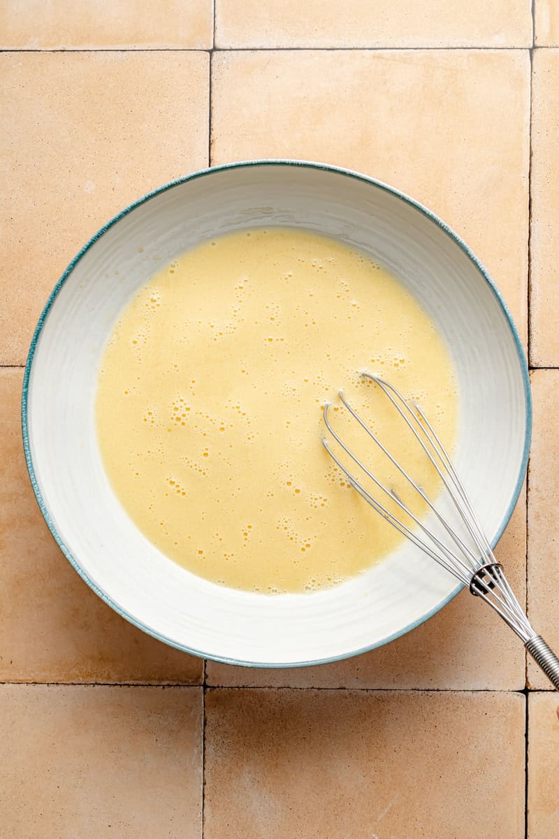 whisking the wet ingredients for oatmeal waffles on a pale pink tile counter.