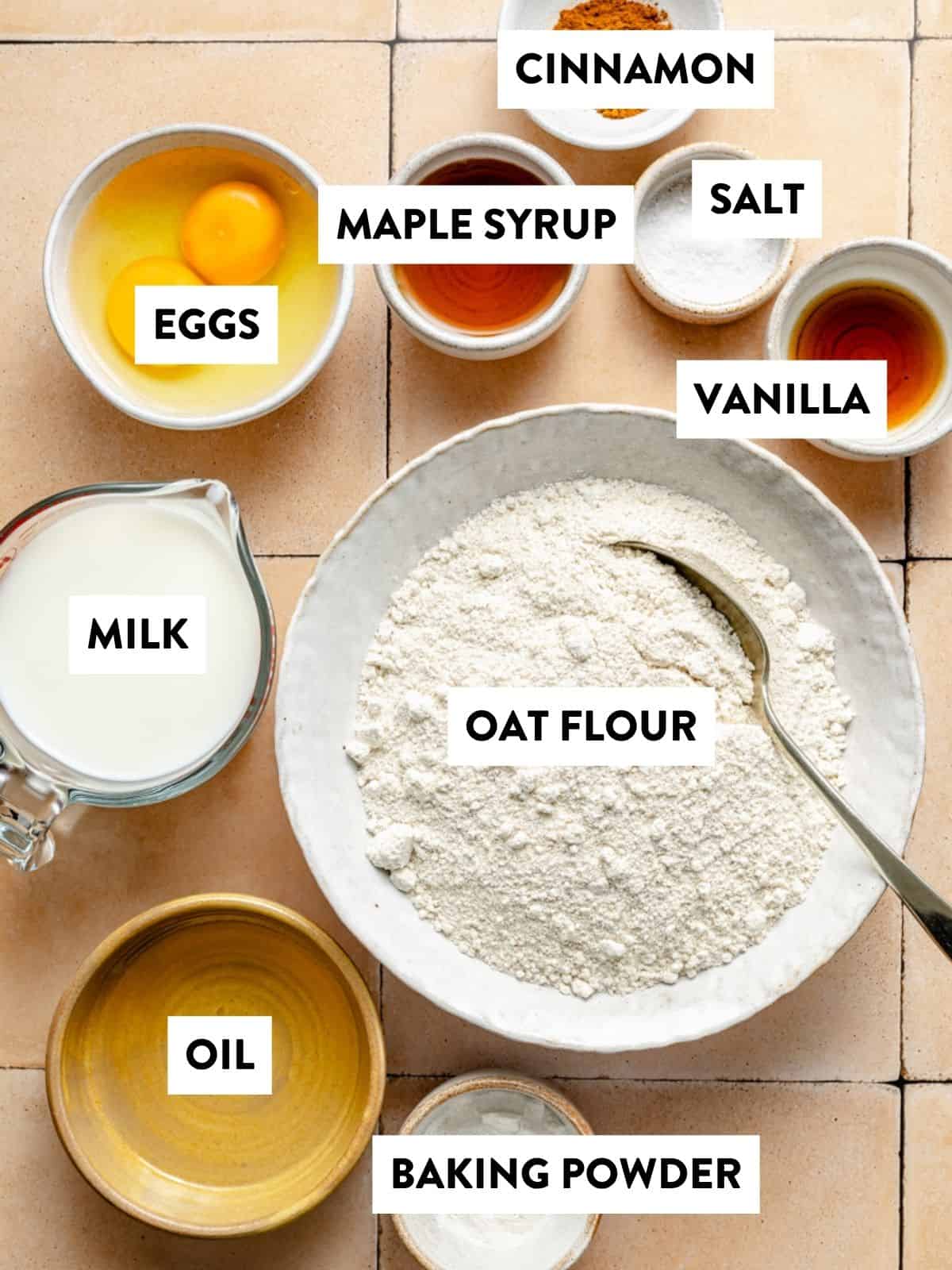 oat flour, oil, milk, eggs, vanilla, salt, and baking powder measured in bowl on a counter for oatmeal waffles.