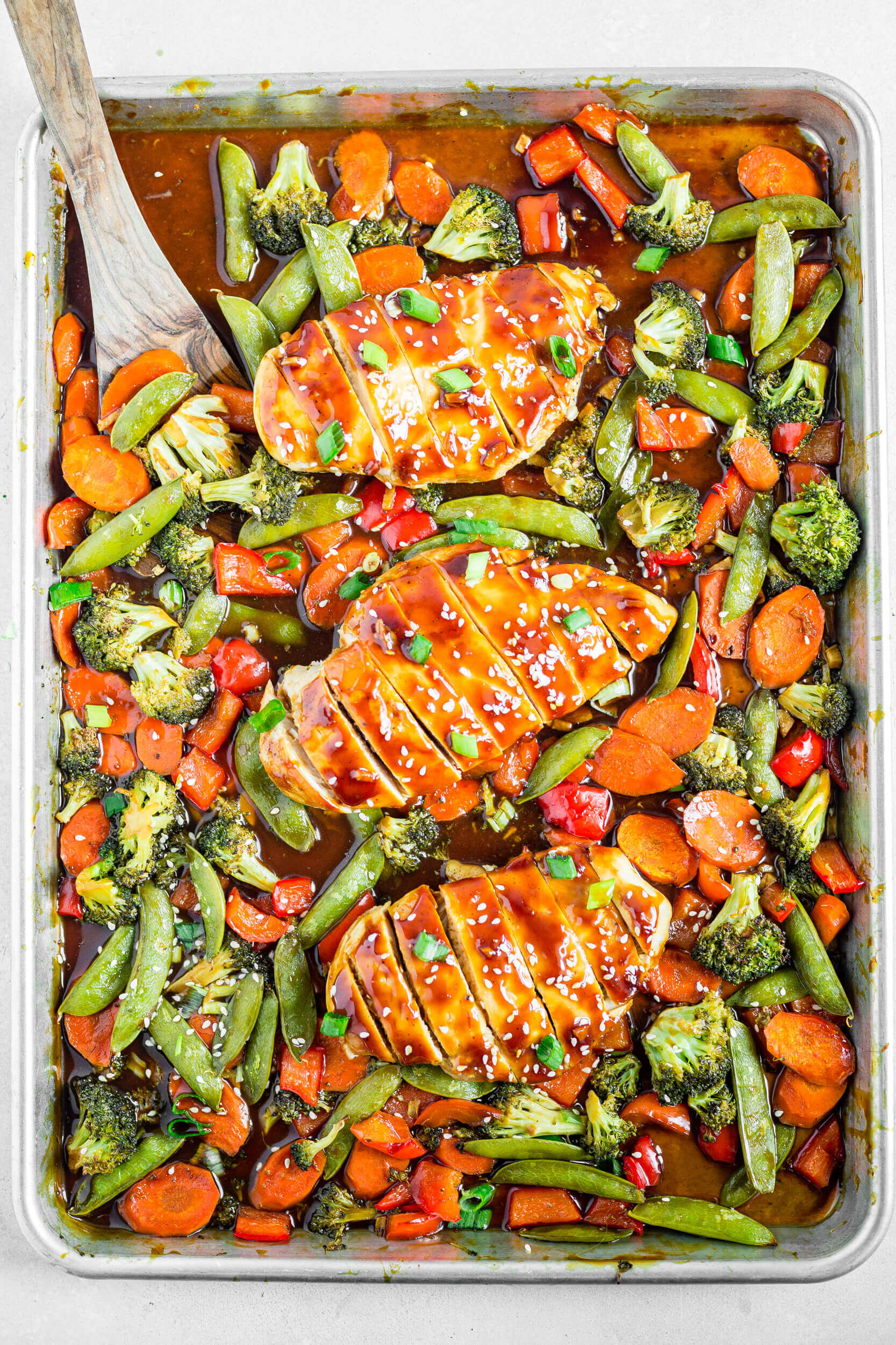 3 pieces of healthy chicken teriyaki on a sheet pan surround by mixed roasted vegetables