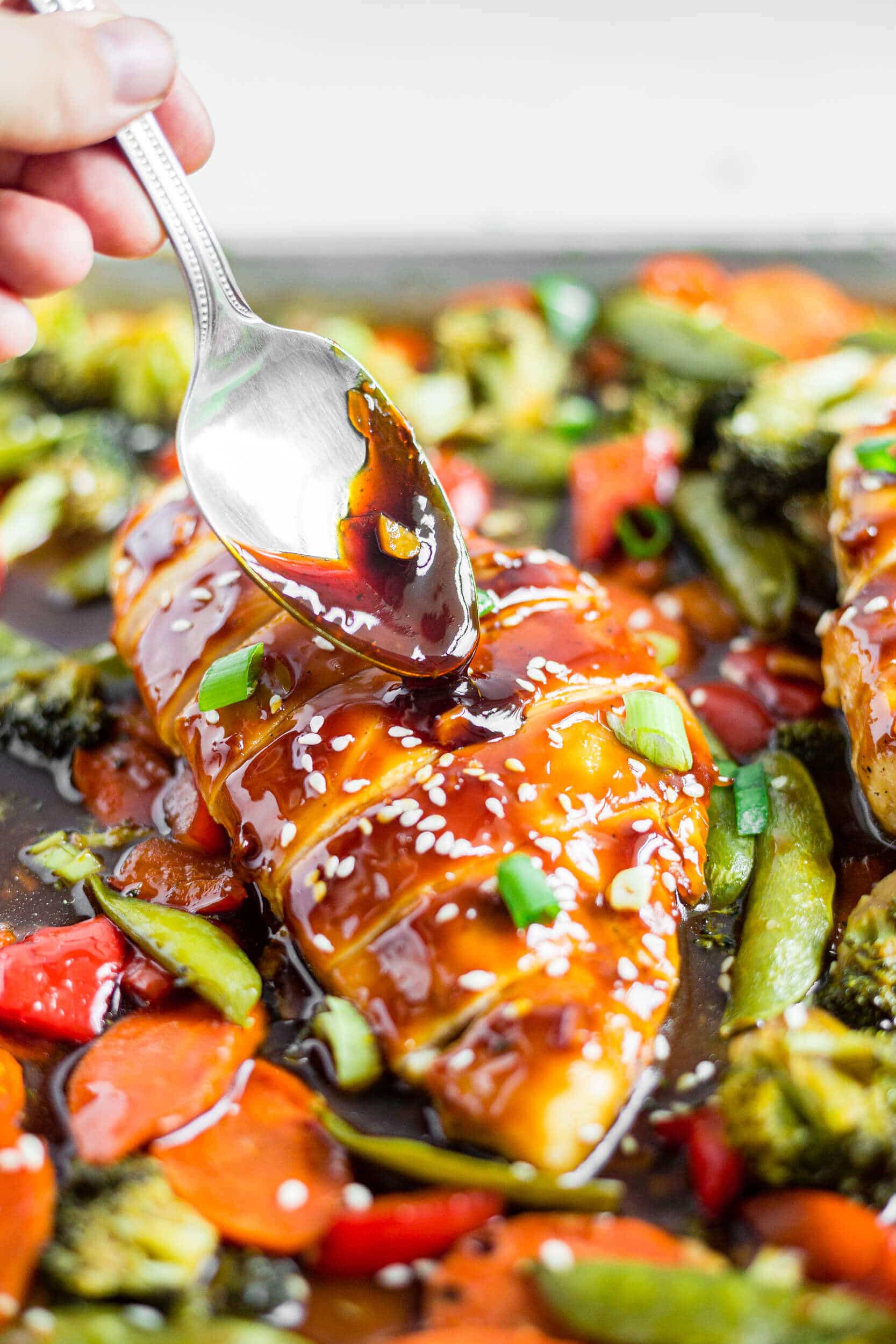 healthy teriyaki sauce being drizzled over a sliced chicken breast and vegetables