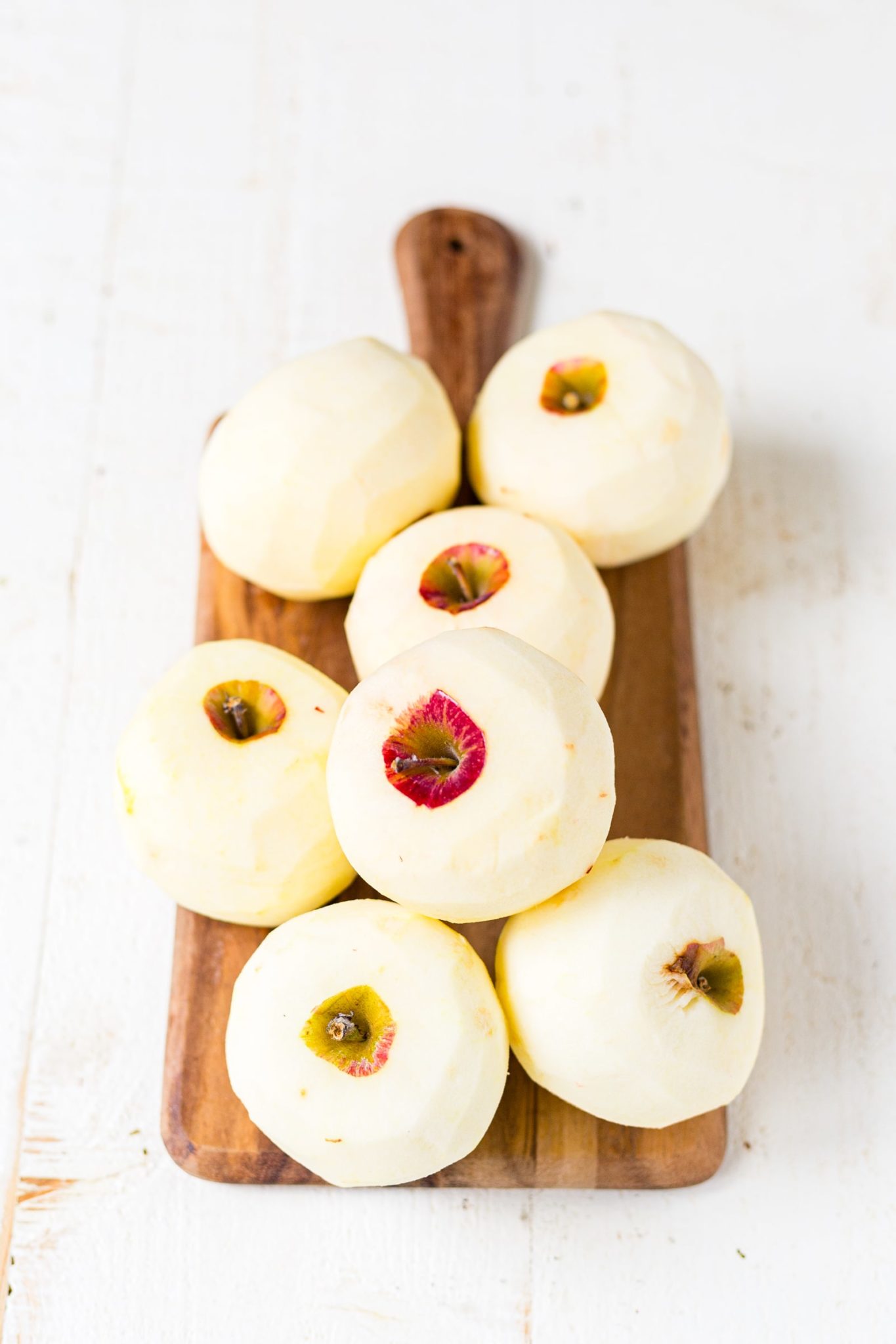 7 peeled apples on a wood cutting board