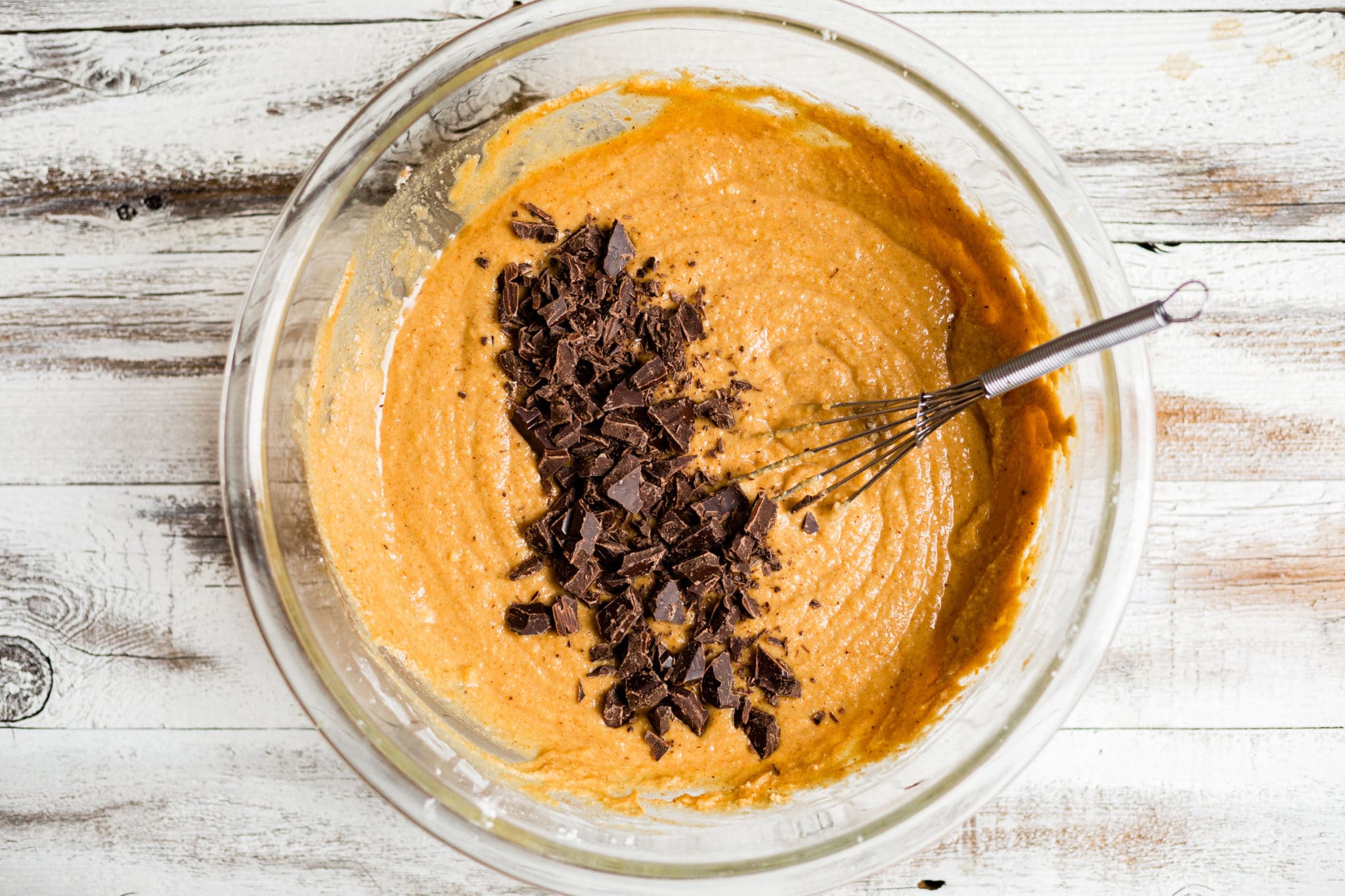 chocolate chunks on top of healthy pumpkin muffin batter