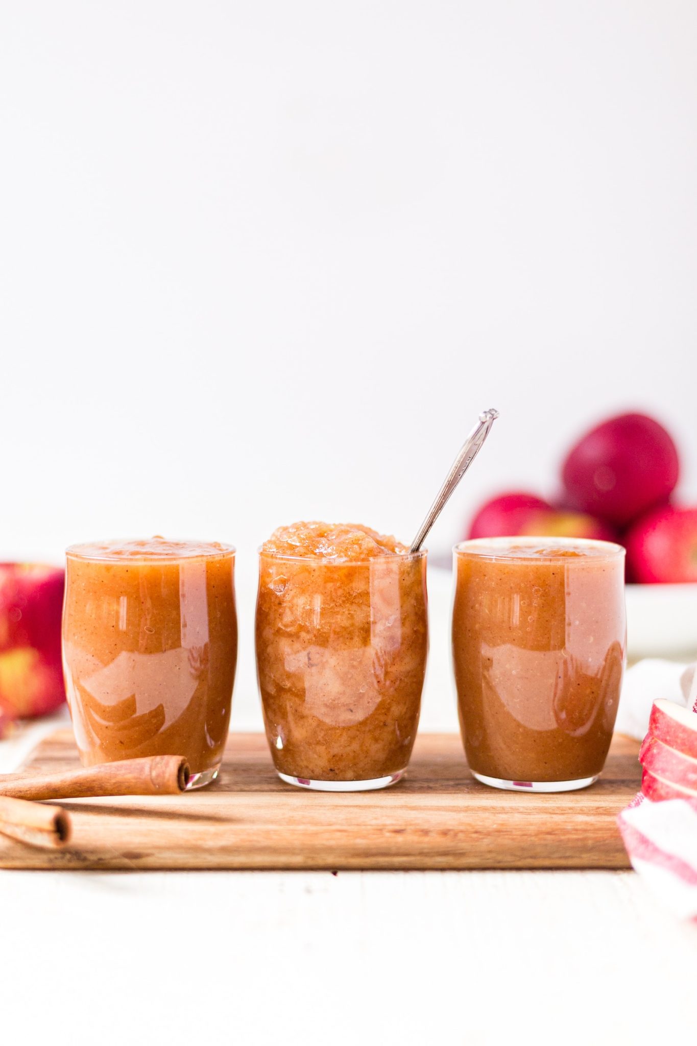 chunky and smooth crockpot applesauce in three jars on a wood cutting board