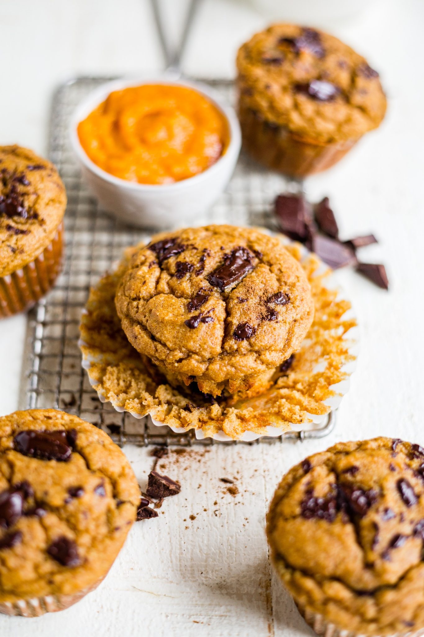 healthy pumpkin muffins on a cooling rack with melted chocolate chunks on top