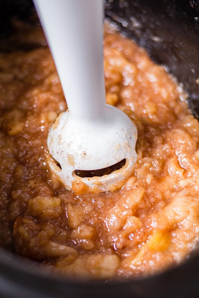 and immersion blender mixing homemade crockpot applesauce when it's still chunky