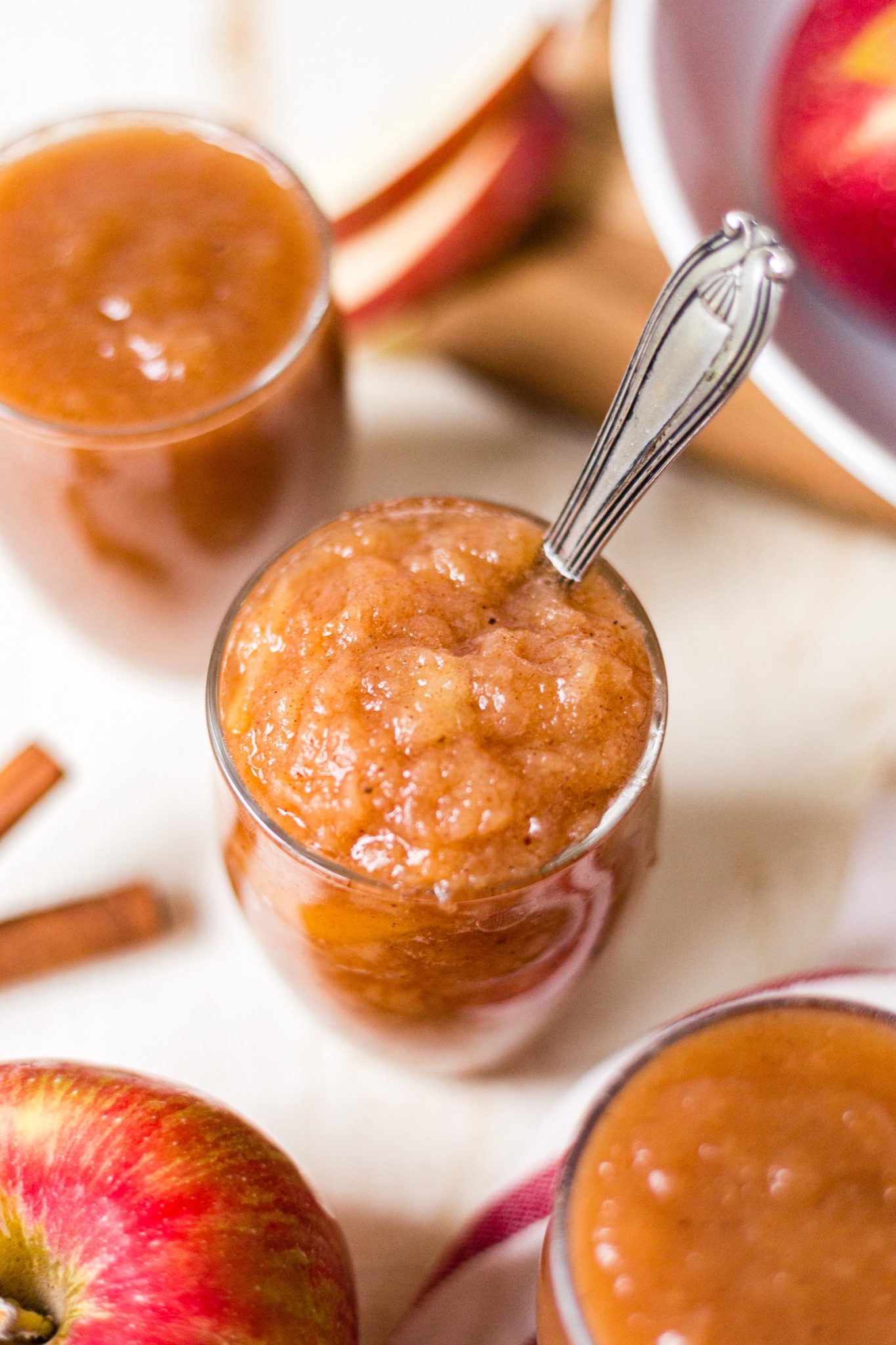 chunky homemade crockpot applesauce in glass cup with a spoon