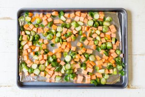 brussels sprouts and sweet potaotes on a sheet pan before roasting