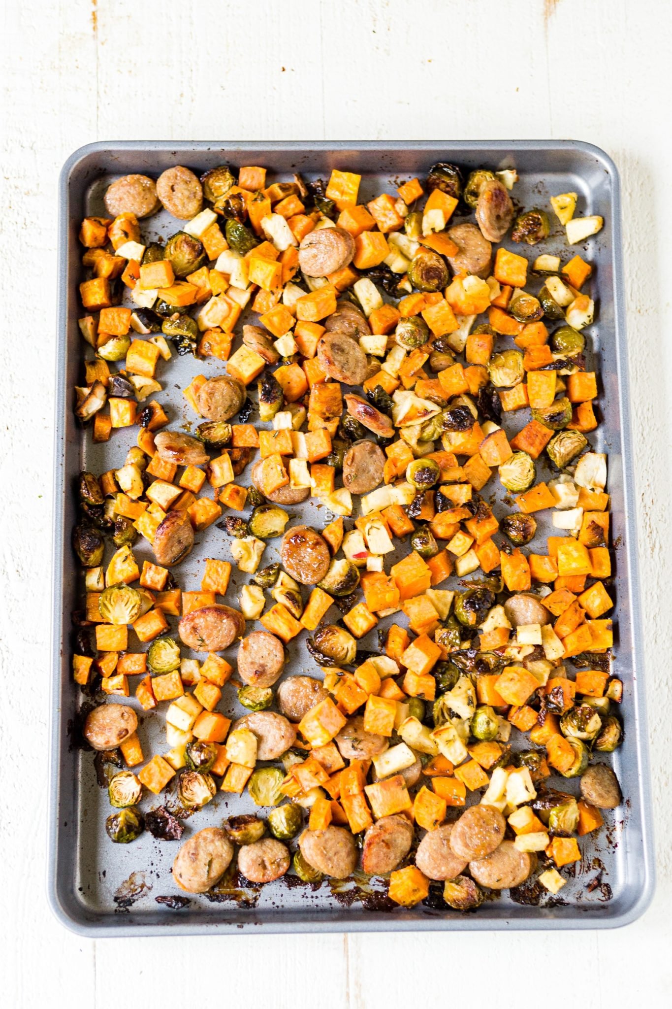 sheet pan filled with roasted sweet potatoes, apples, brussels sprouts and chicken sausage
