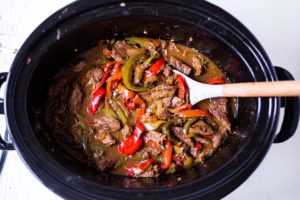 slow cooker pepper steak with a serving spoon