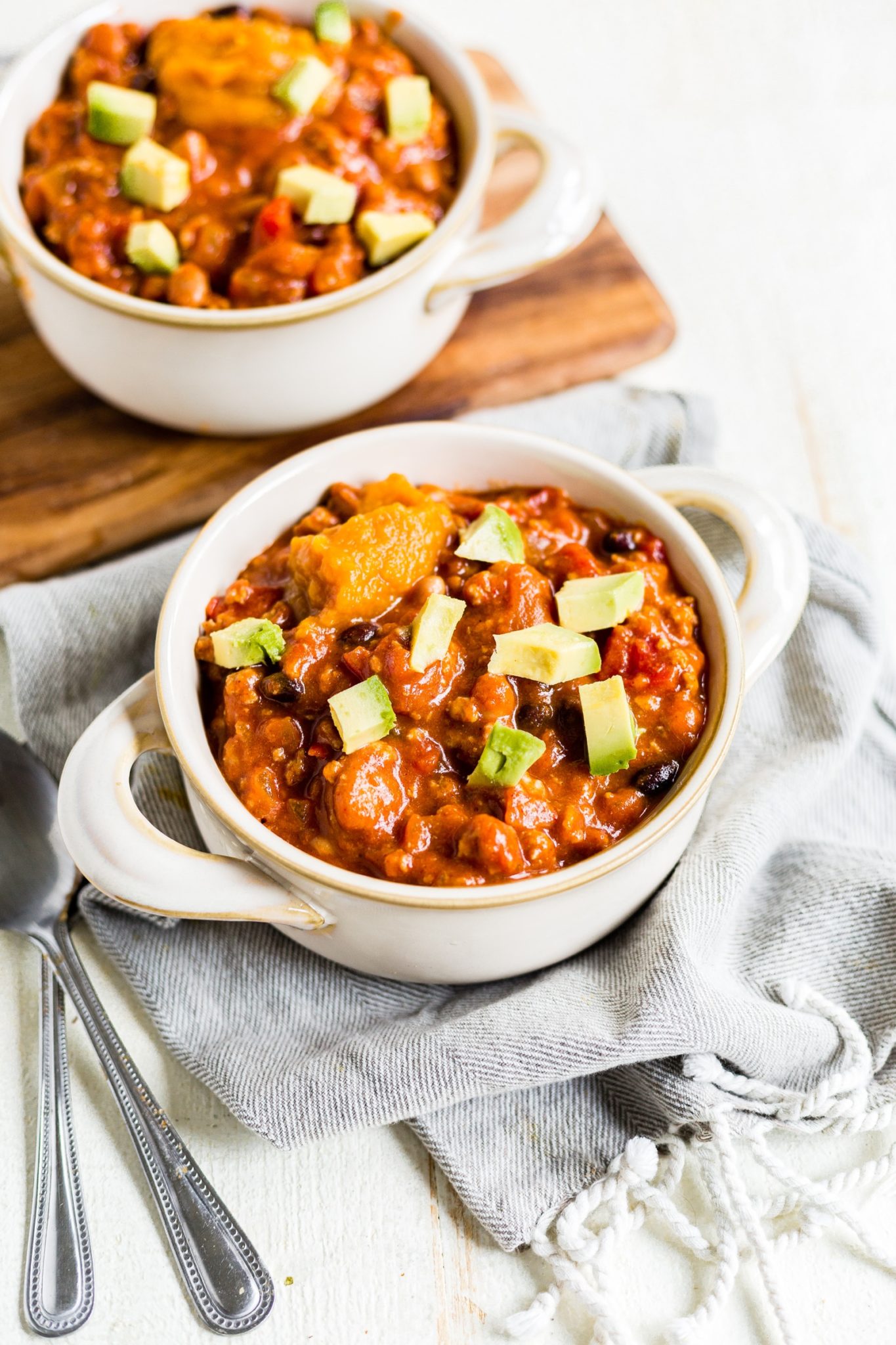 two bowls of turkey pumpkin chili with diced avocado