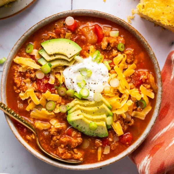 a bowl of turkey pumpkin chili topped with avocado, sour cream, and cheese.