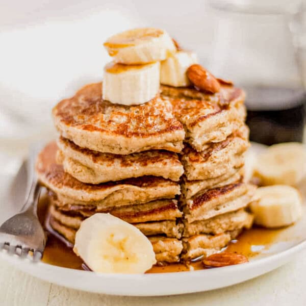 a stack of banana oat pancakes on a plate with syrup.