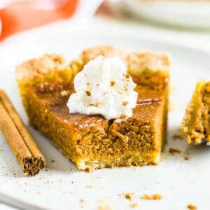 dairy free pumpkin pie on a white plate with a bite taken out of one
