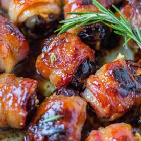 bacon wrapped dates in a pan with honey glaze and rosemary