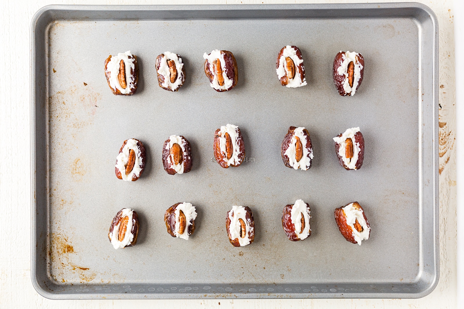 pecans stuffed inside dates with goat cheese on a baking pan