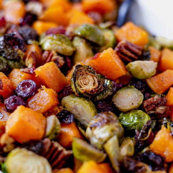 roasted brussel sprouts and butternut squash in a serving dish with pecans and cranberries