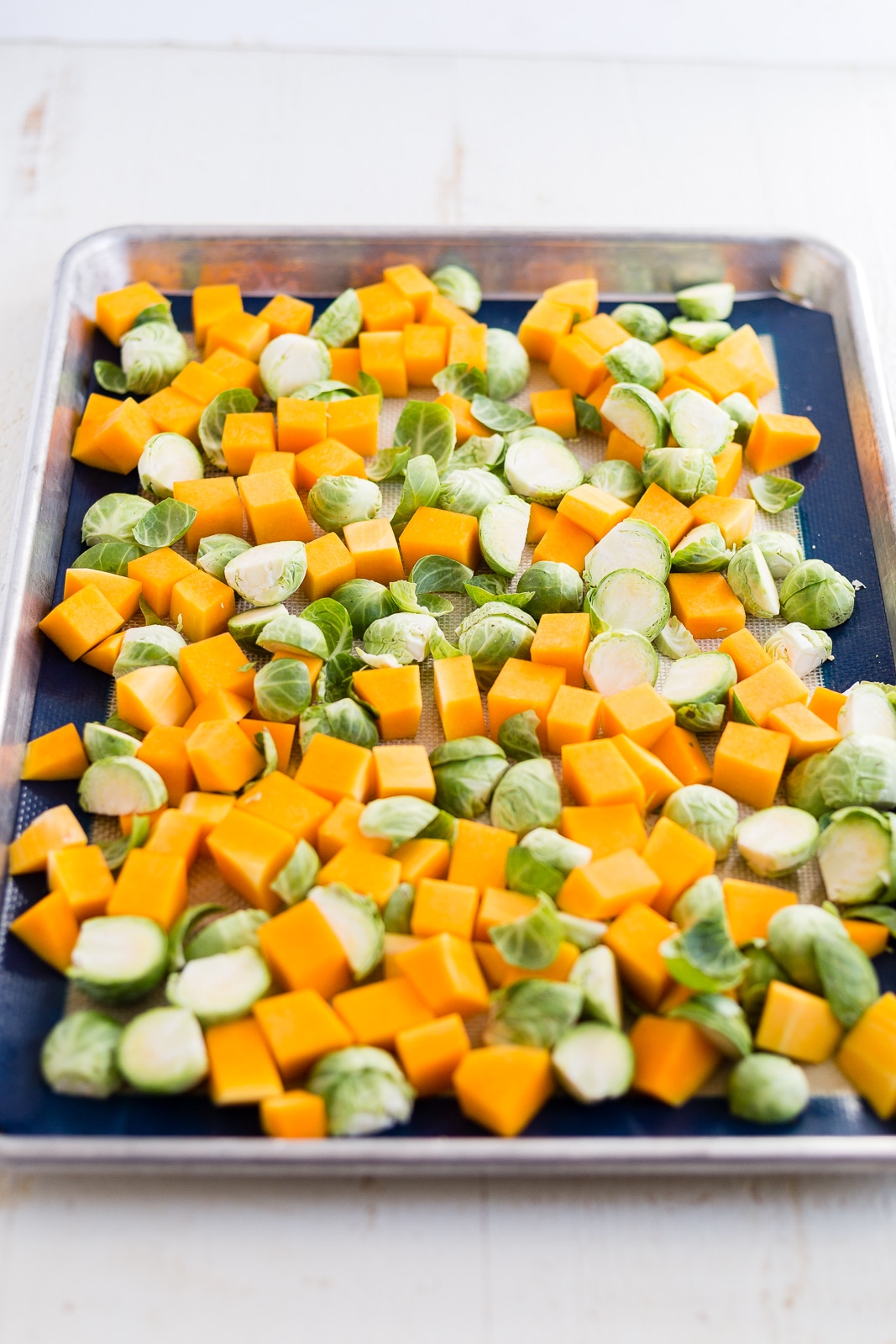 brussel sprouts and butternut squash on a sheet pan before roasting