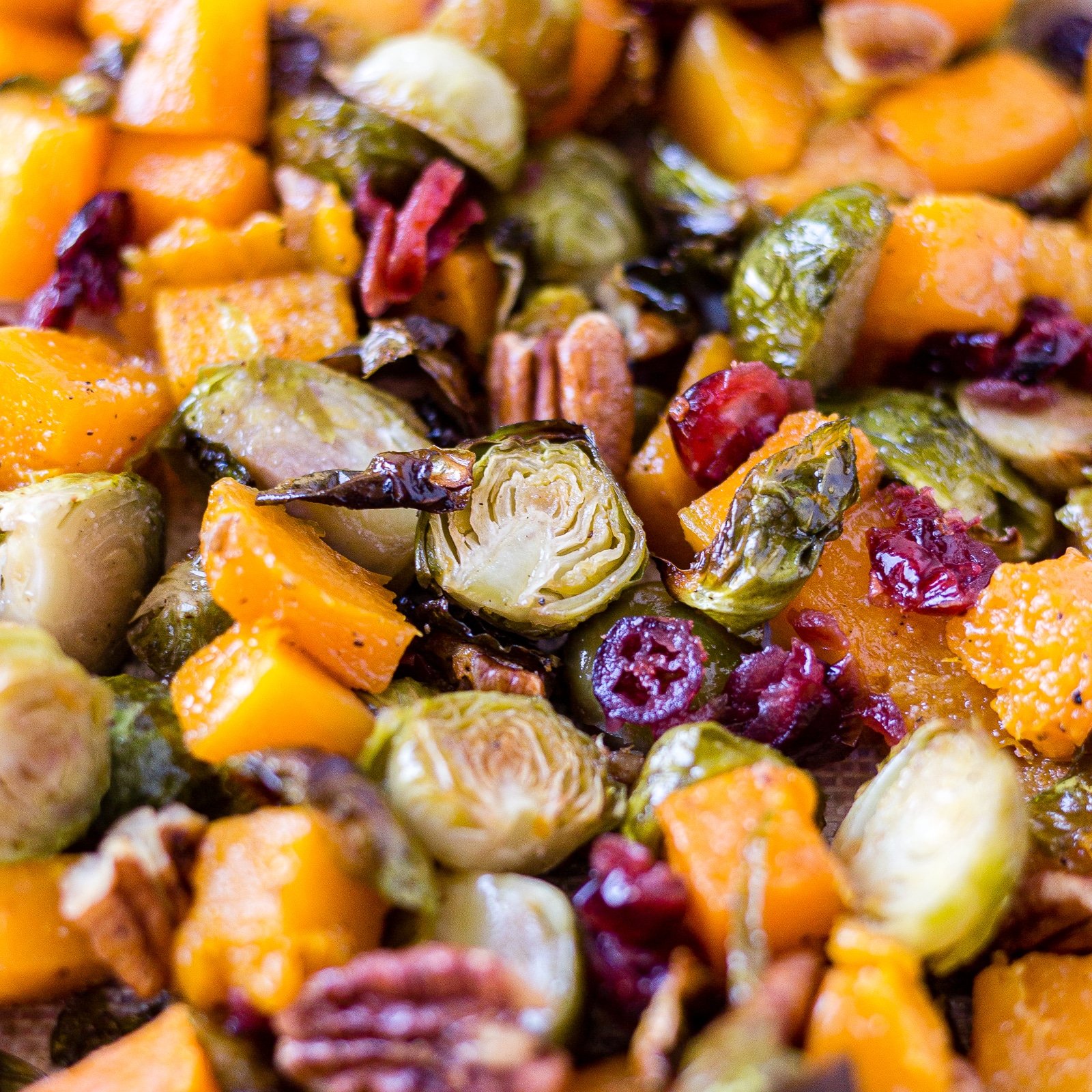 brussel sprouts and butternut squash on a sheet pan with pecans and cranberries