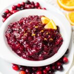 healthy cranberry sauce recipe in a white serving dish with orange zest on top