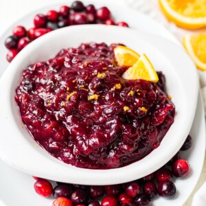 healthy cranberry sauce recipe in a white serving dish with orange zest on top