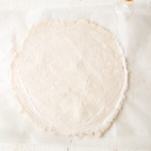 gluten free pie crust rolled into a circle between parchment paper