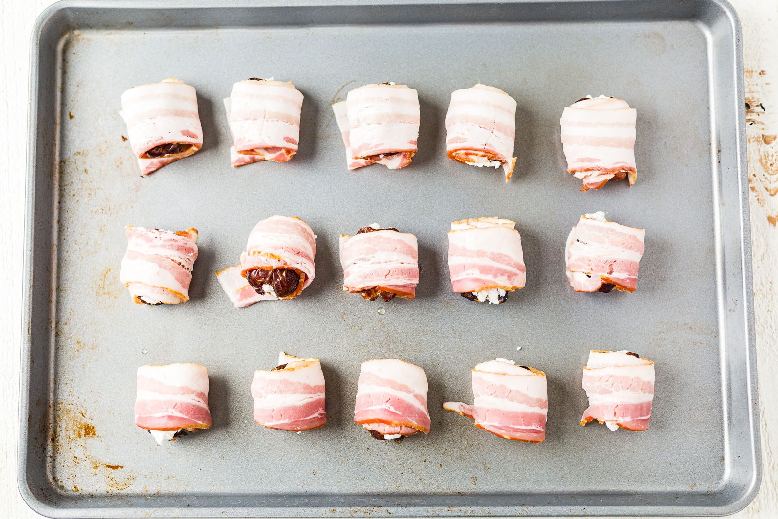 bacon wrapped dates on a baking pan before cooking
