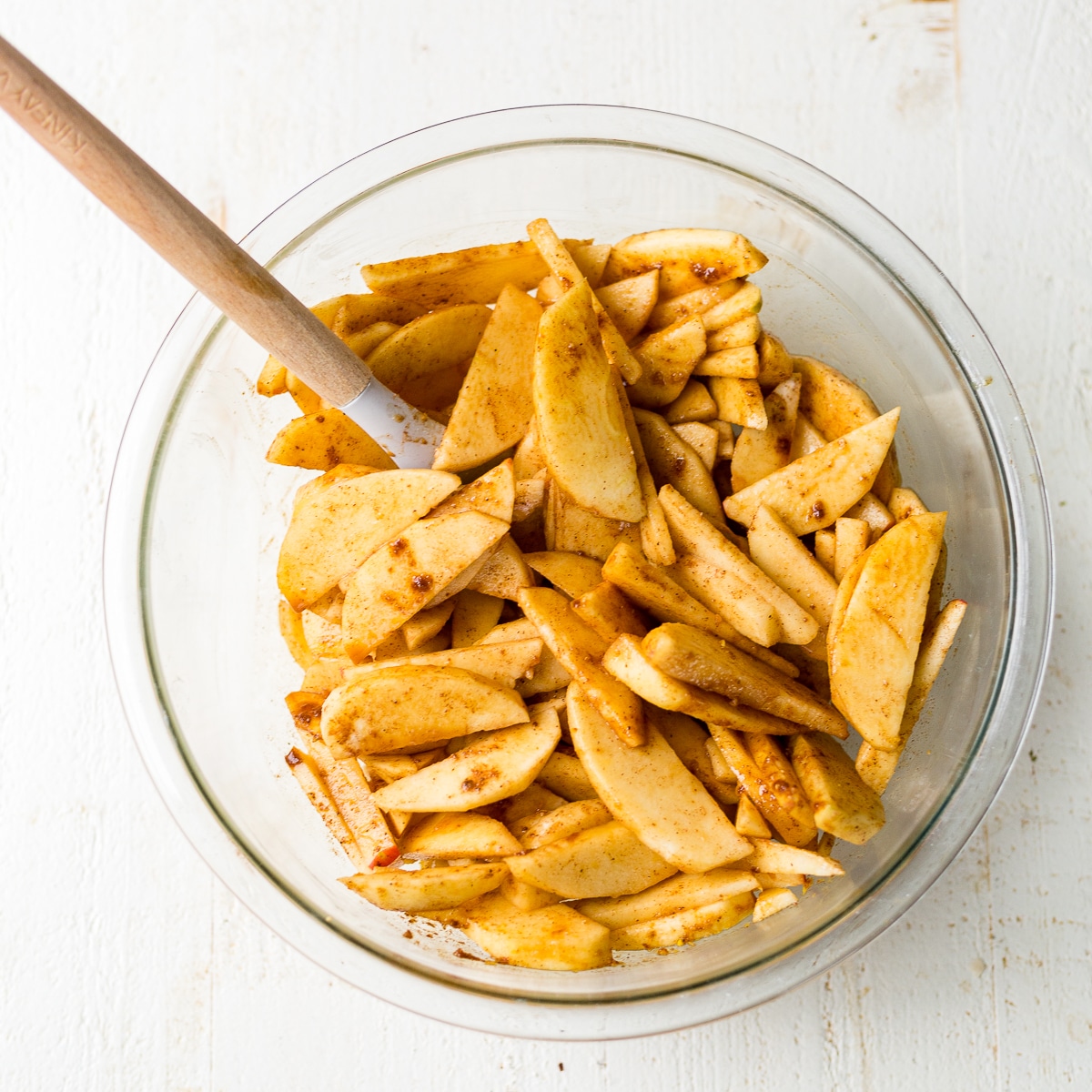 gluten free apple pie filling in a glass bowl with a rubber spatula