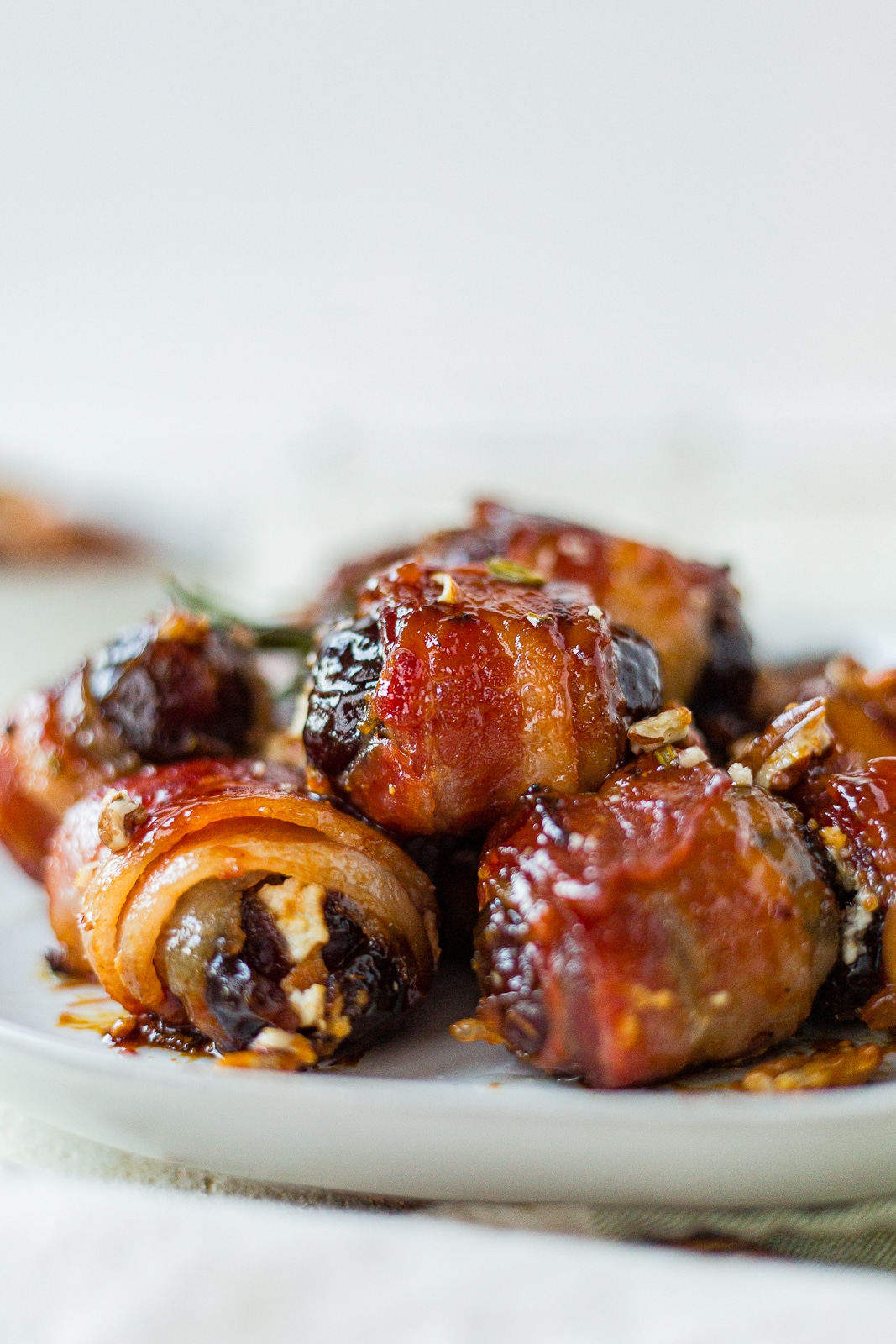 close up of bacon wrapped dates on a white serving platter