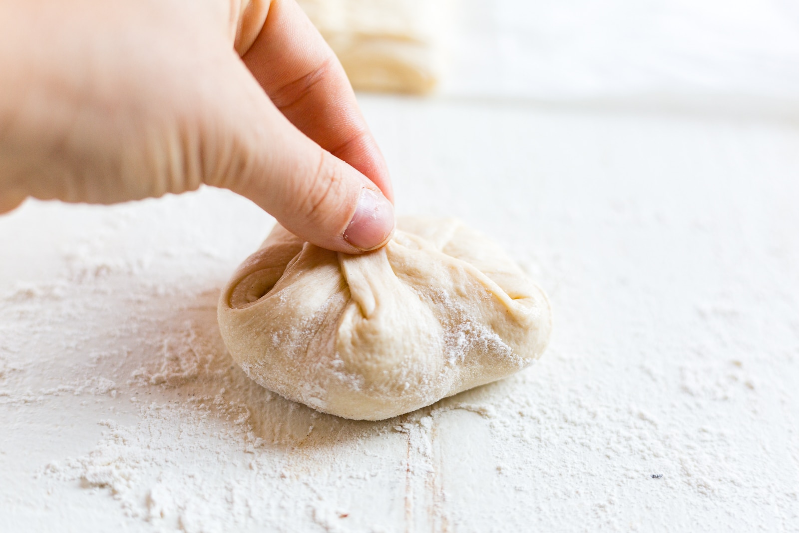 hand pinching sourdough rolls to shape them before baking