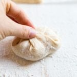 hand pinching sourdough bun dough together before rolling and baking