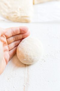 hand rolling sourdough bun dough into a smooth ball before baking