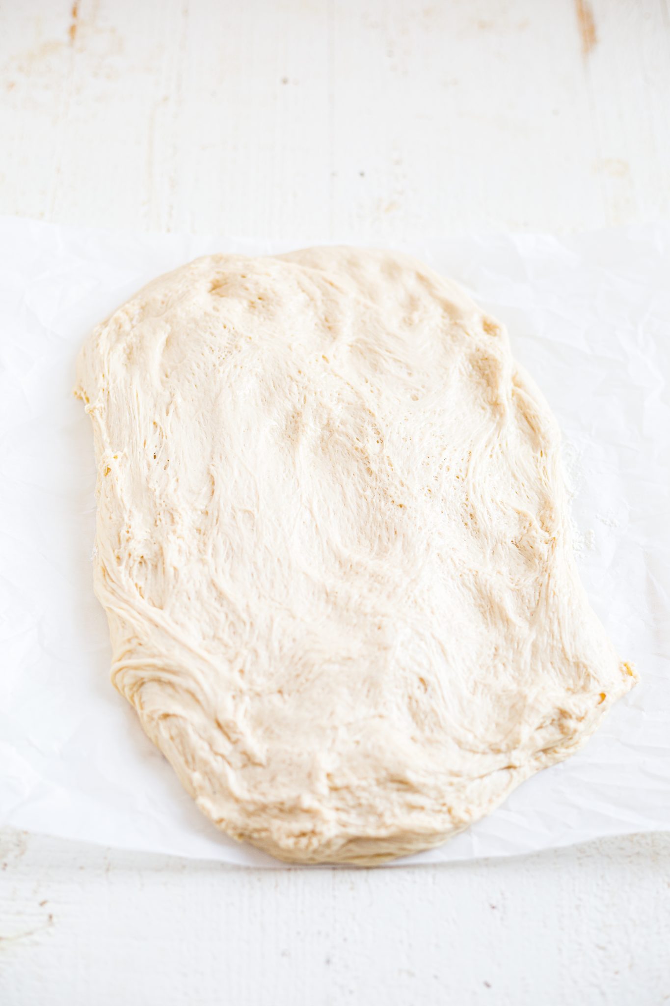 sourdough bun dough spread out onto a lightly floured surface