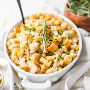 sourdough stuffing recipe in a white serving dish with fresh rosemary on top