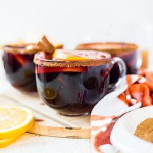 warm winter sangria in a glass mug topped with fresh oranges, apples and cinnamon sticks