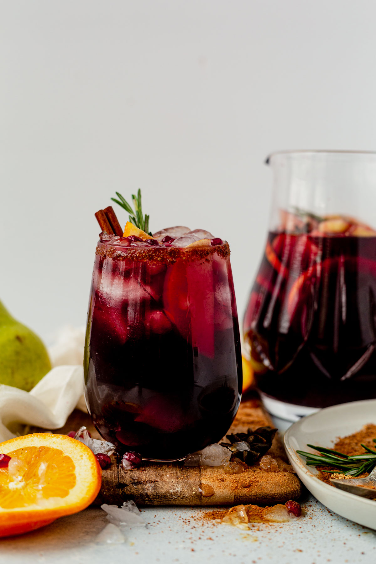 winter sangria in a wine glass with cinnamon sticks and rosemary