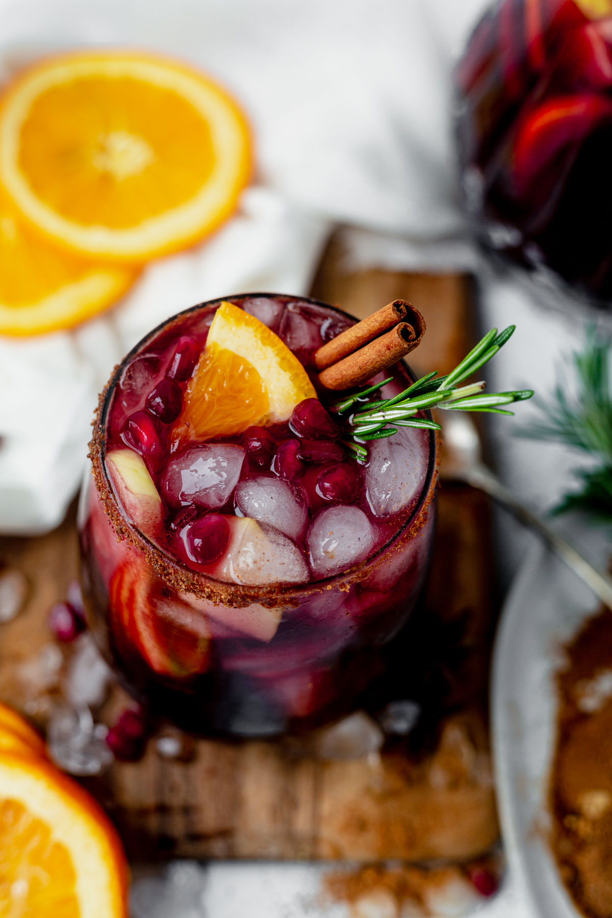 winter sangria in a wine glass with ice, cinnamon sticks and oranges