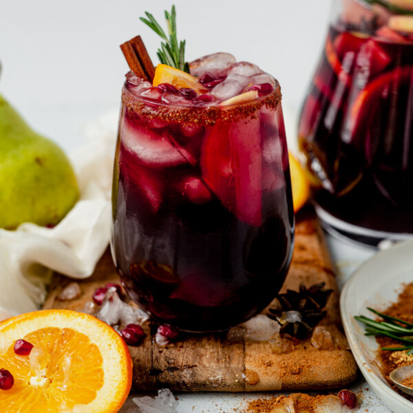 a glass of winter sangria with fresh rosemary and cinnamon sticks
