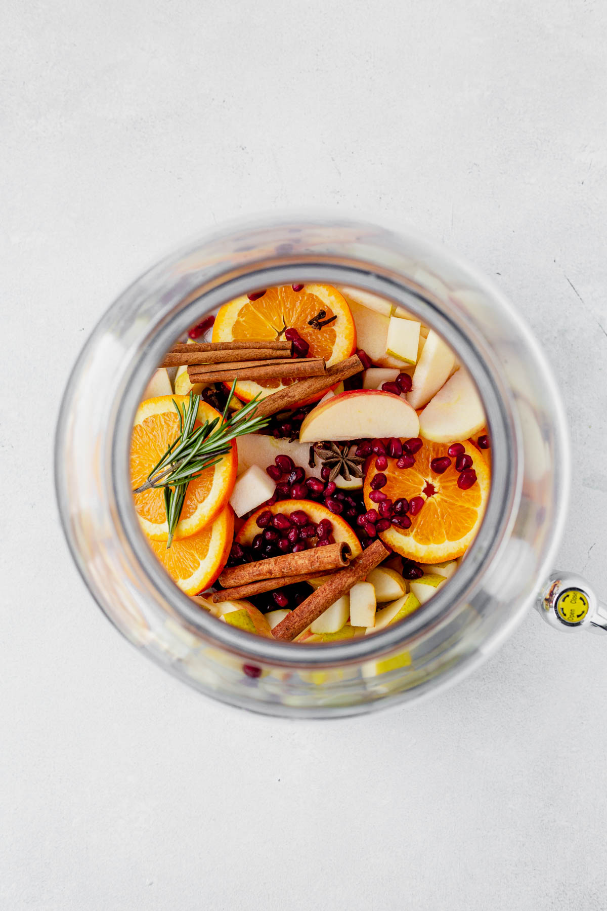 winter sangria fruit in a pitcher with rosemary and cinnamon sticks