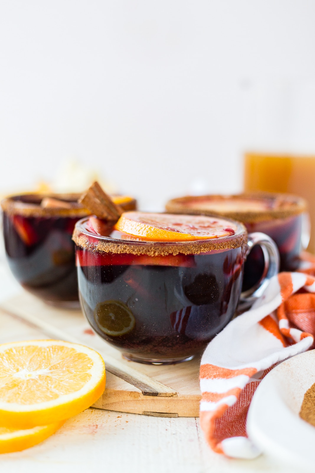 winter sangria in a clear mug topped with fresh oranges, apples and a cinnamon stick