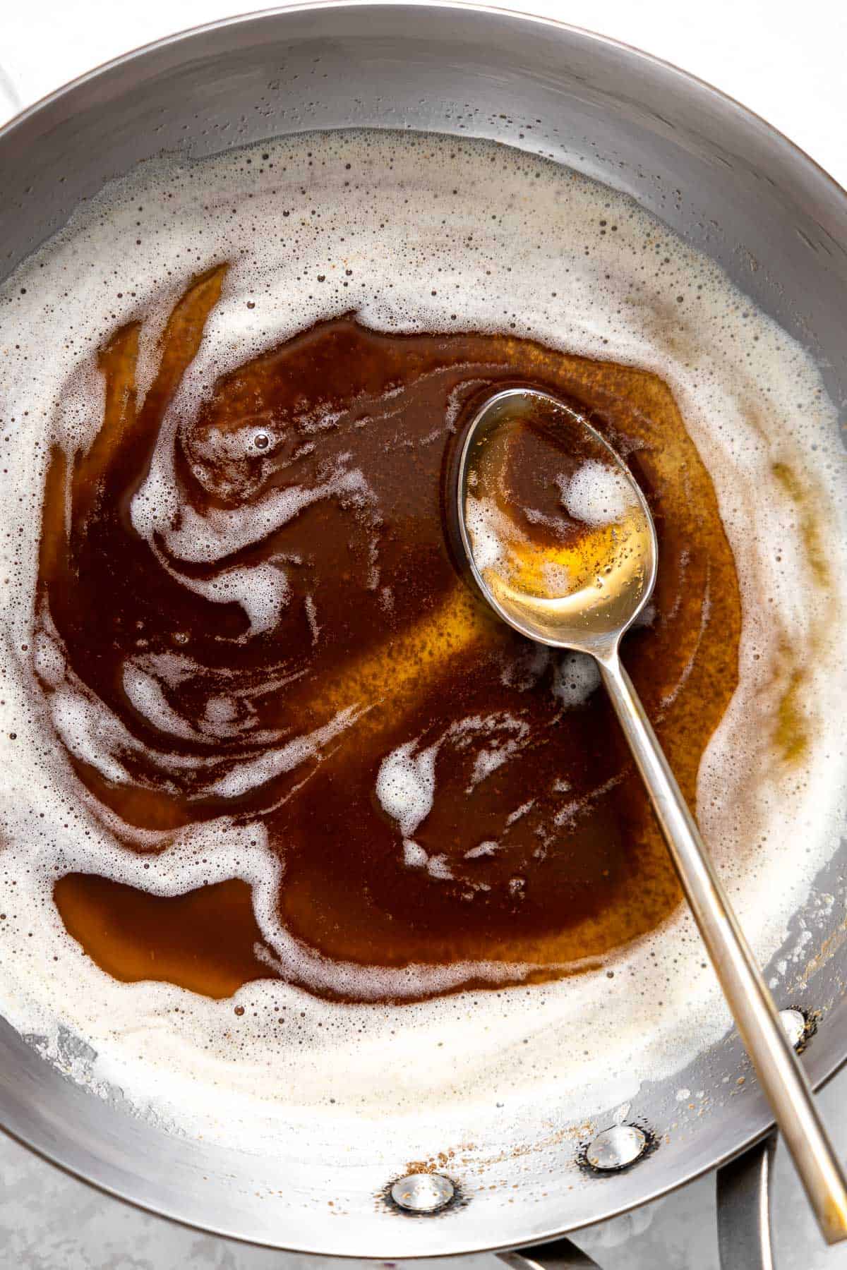 brown butter swirling in a pan with a spoon.