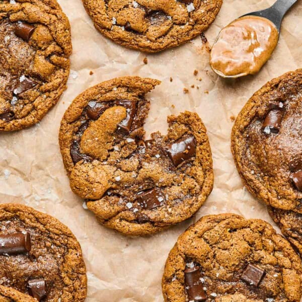 an almond butter chocolate chip cookie broken in half on parchment paper.