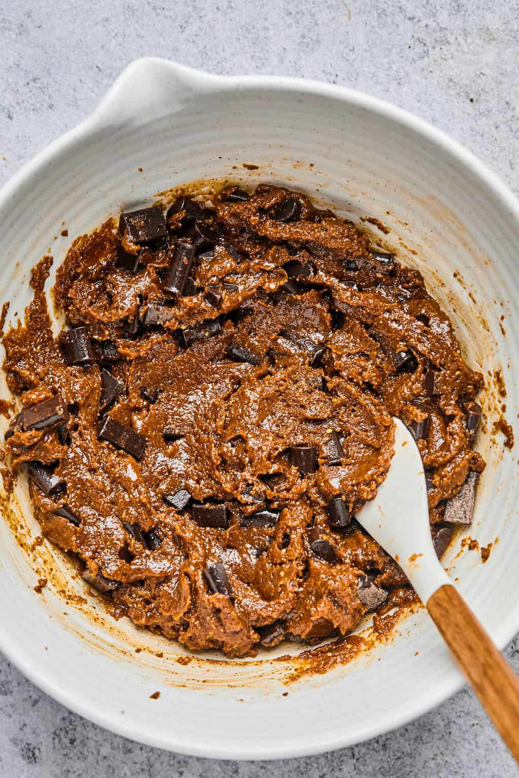 stirring chocolate chips into almond butter cookie dough.