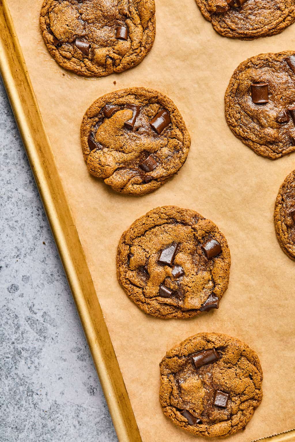 freshly baked almond butter chocolate chip cookies cooling on a sheet pan.