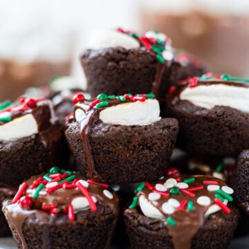 close up of hot cocoa cookies stacked on top of each other with chocolate ganache dripping down the sides