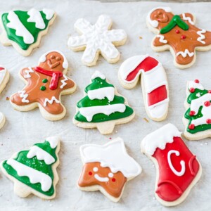 10 gluten free sugar christmas themed cookies on a baking sheet decorated for christmas with royal icing