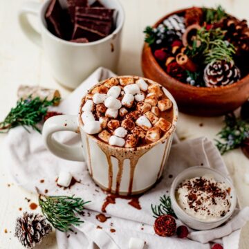 a white mug overflowing with dairy free hot chocolate and topped with mini marshmallows
