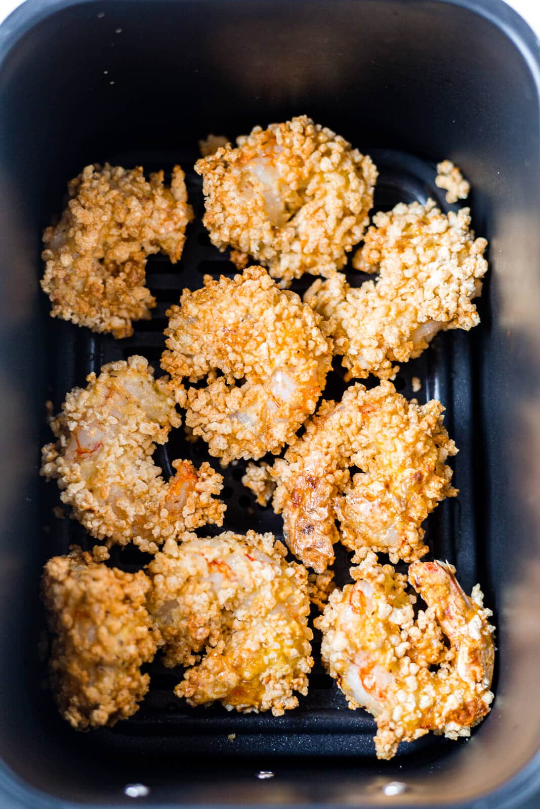 crispy air fryer shrimp sitting in the air fryer basket after being cooked